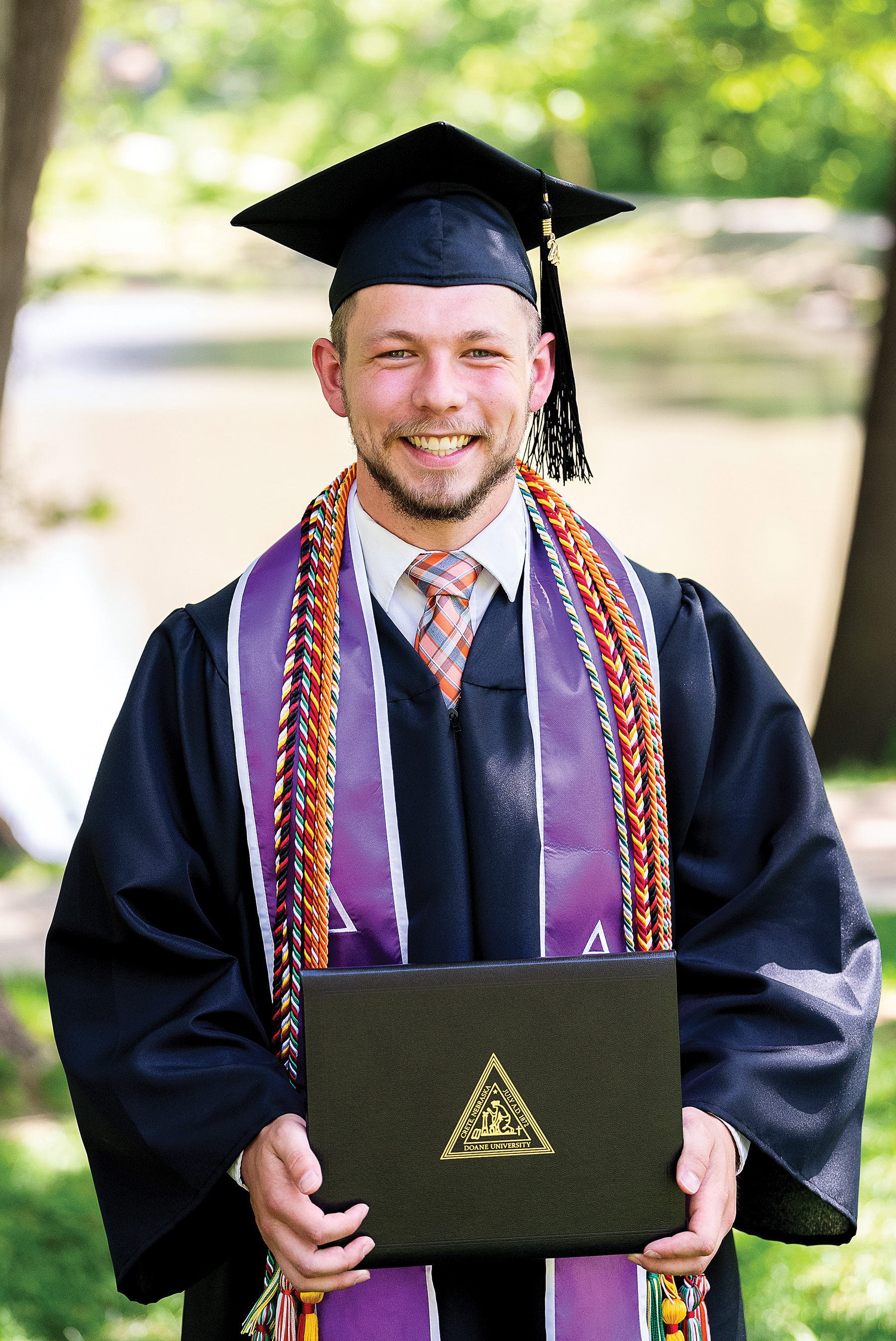 Juan "Zack" Perez stands holding his diploma as a proud graduate.